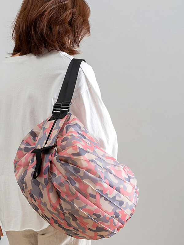 Woman carrying a colorful camo-pattern sports shoulder bag, lightweight and waterproof, perfect for fitness activities.